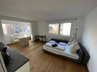 Minimalist bedroom with a large comfortable bed, simple decor, bright windows, and a hint of urban surroundings outside